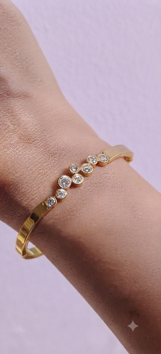 Gold-tone bangle with bezel-set stones, worn on the wrist